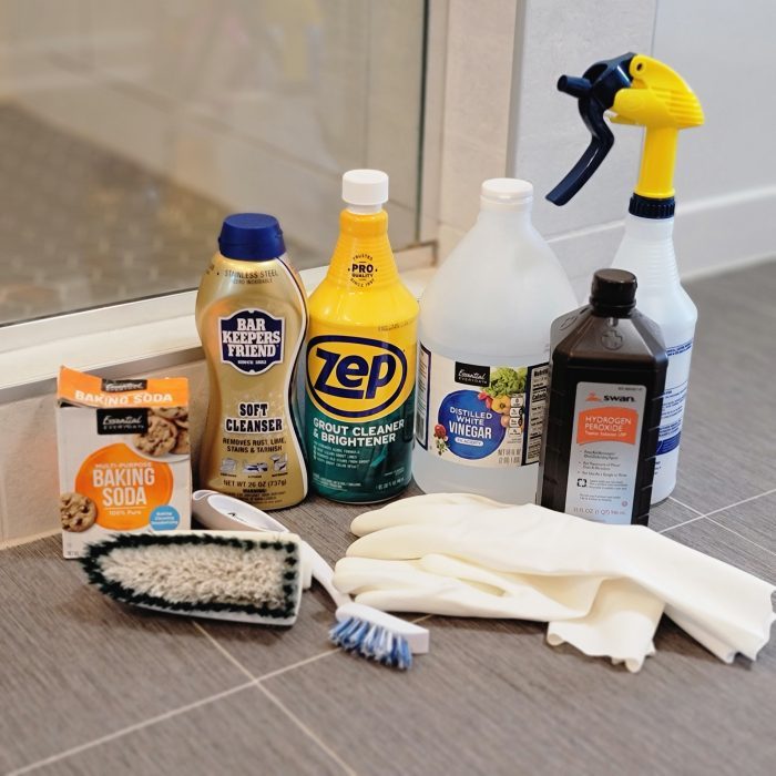 各种瓷砖和灌浆清洁产品和工具在浴室的地板上