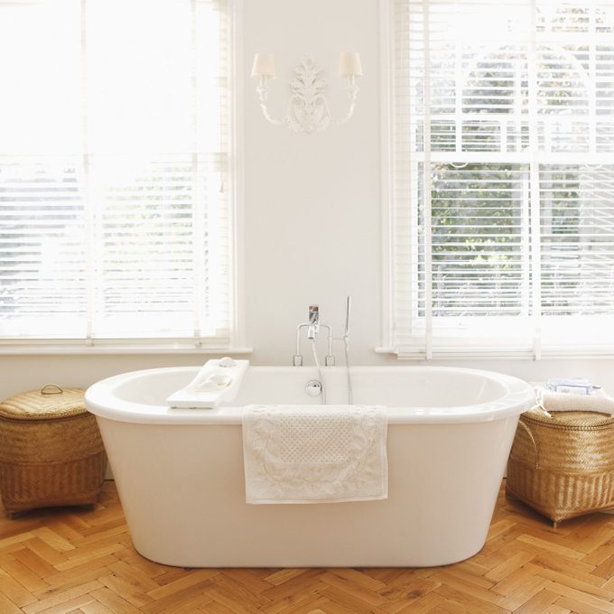 freestanding bath tub in bathroom near windows